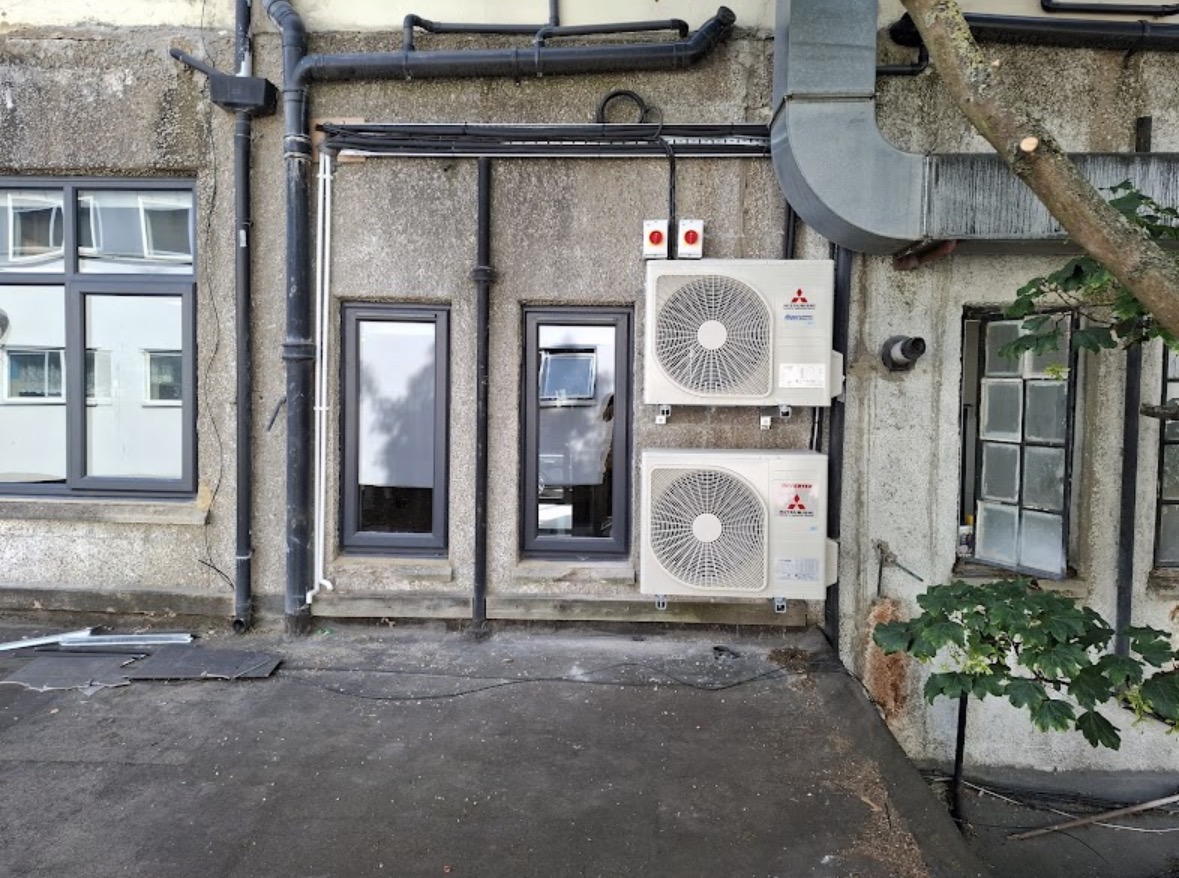 Twin Mitsubishi outdoor condenser units installed on rear wall